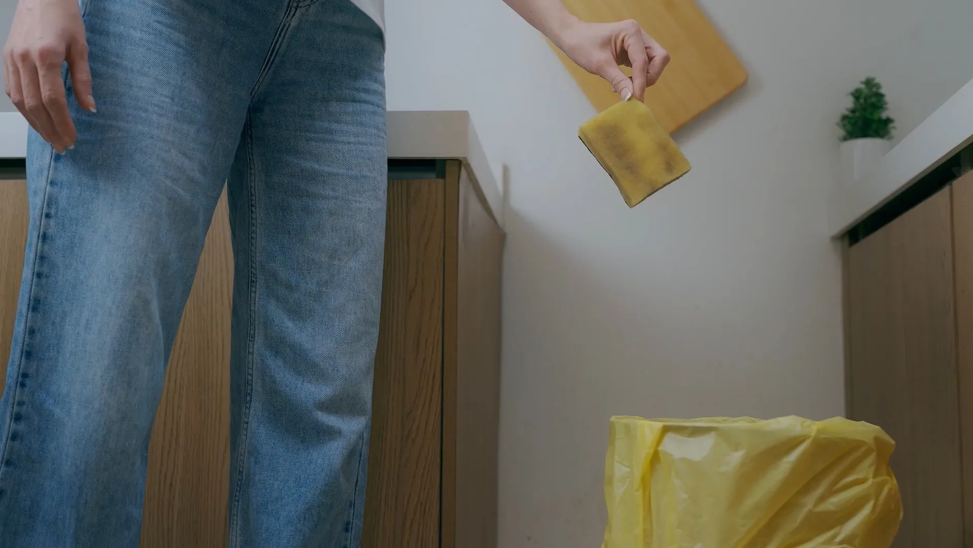 A used sponge dropped into the kitchen trash bin