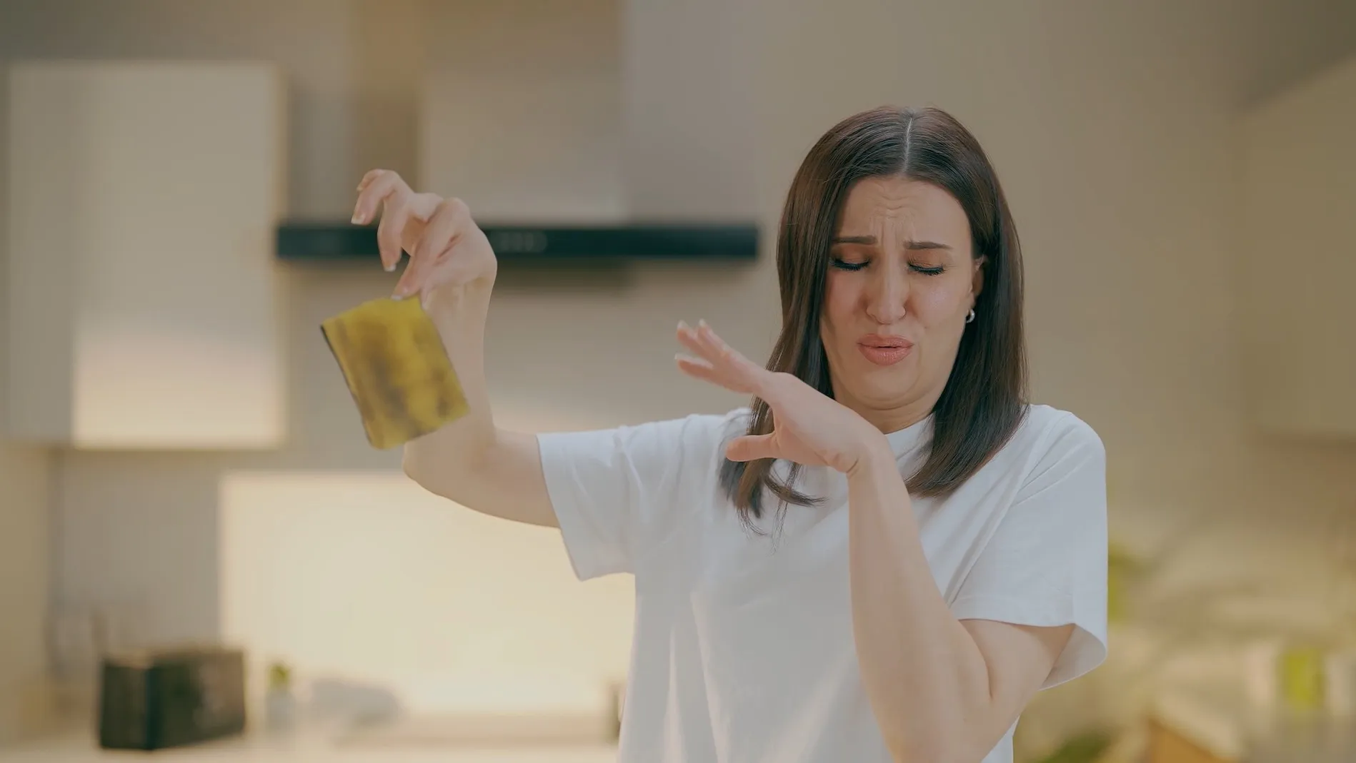 Woman holding a smelly kitchen sponge at arm's length