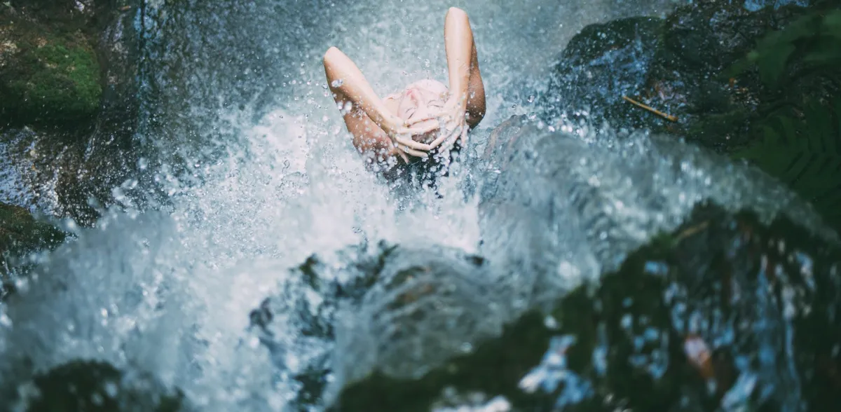 showering lady under a small falls